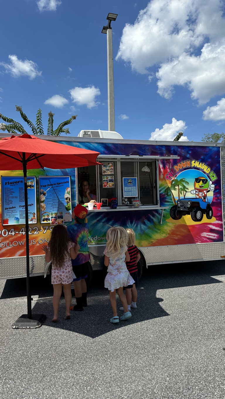 Kids ordering Top Down Shaved Ice under a red umbrella.